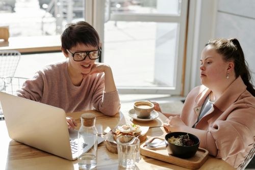 Two friends sharing breakfast and coffee at a cozy cafe, relaxed and happy.